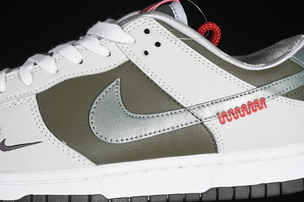 Close-up of white overlays, olive side panel, silver Swoosh, and red stitching detail.