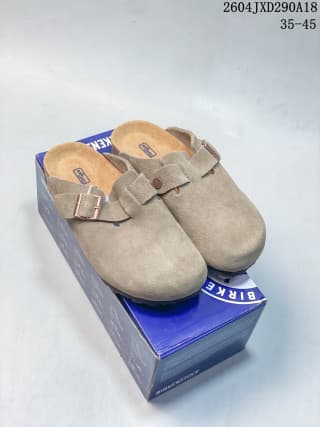 Pair of beige suede Boston-style clogs displayed on top of the branded blue box.