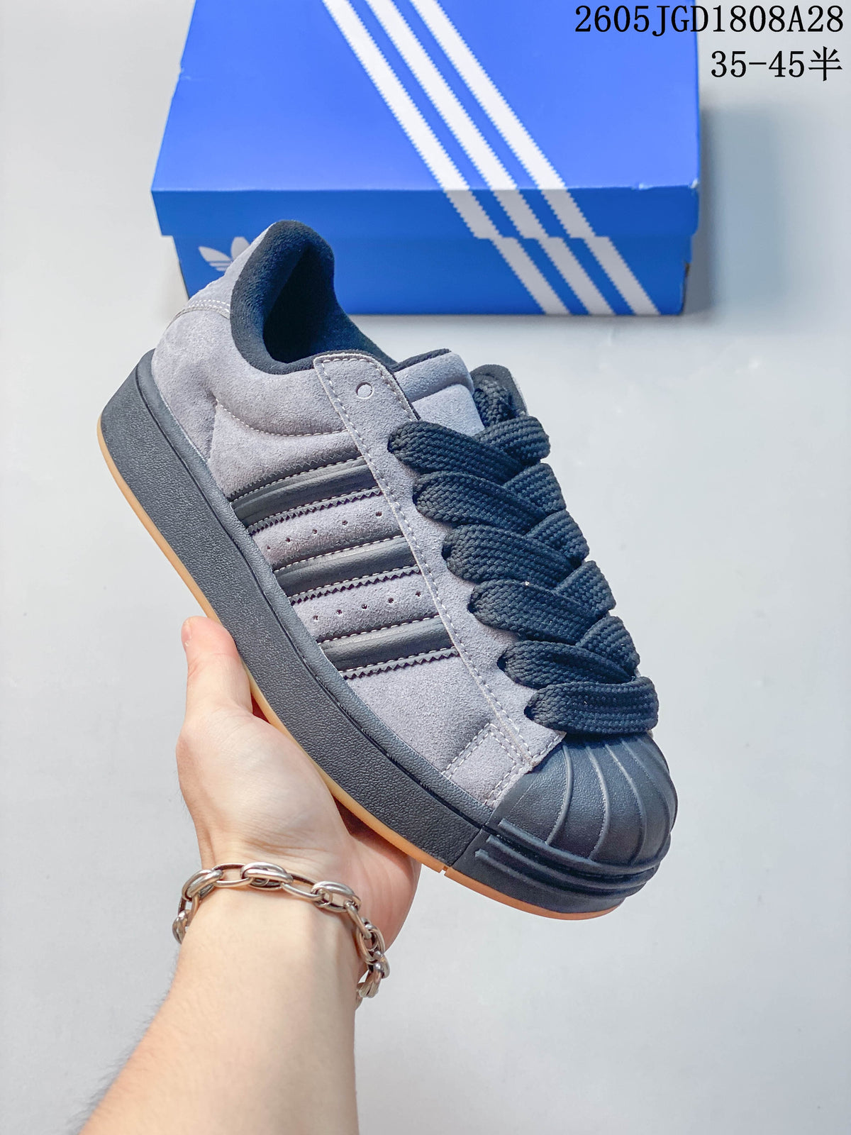 Angled side view of the grey shoe with dark stripes and a shell toe.