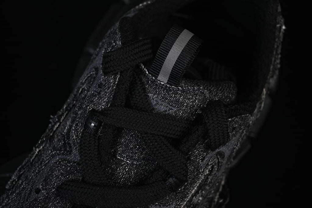 Top view of the black sneaker's laces, tongue, and pull tab.