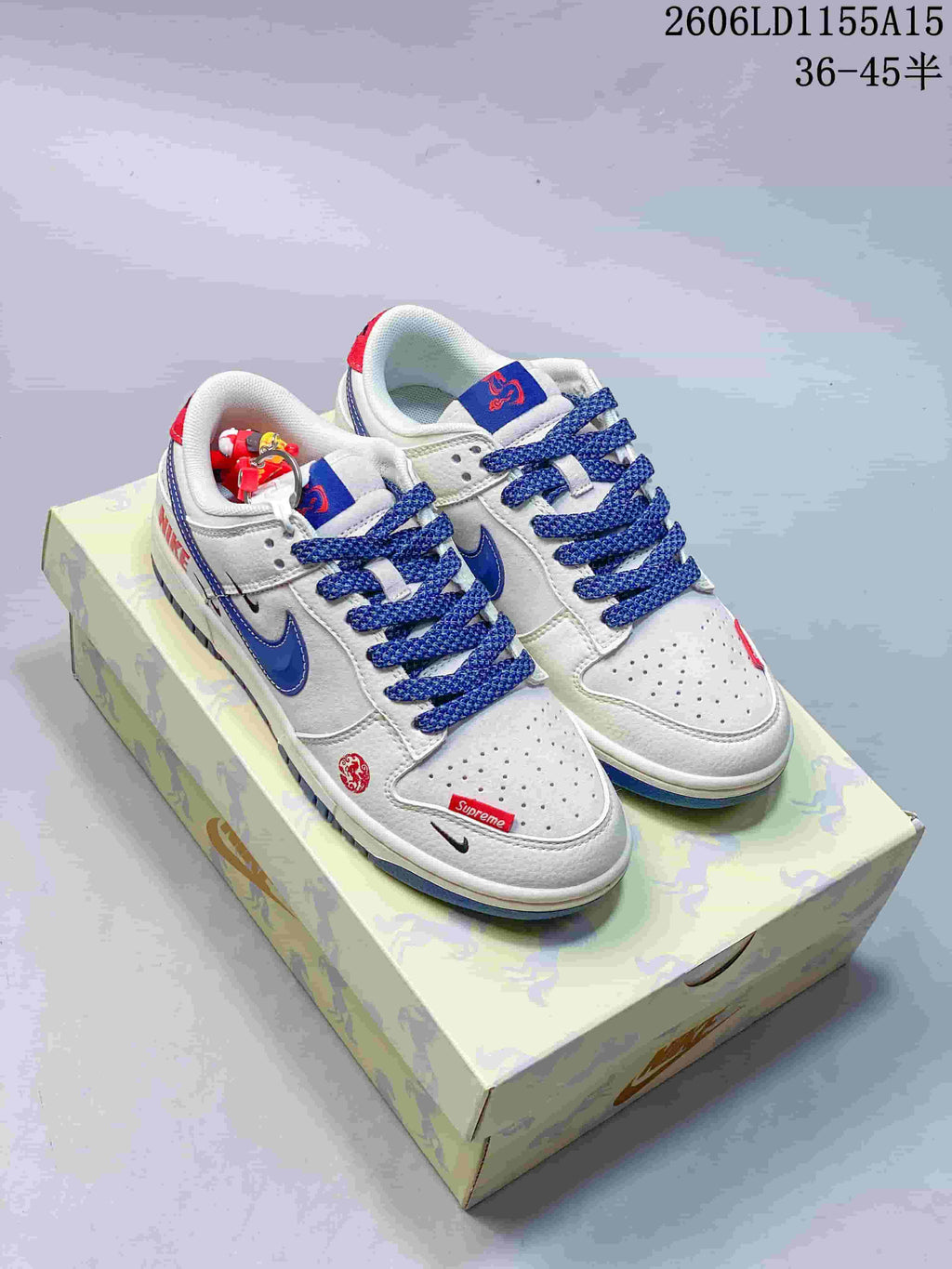 Pair of white and blue low-top sneakers with red accents displayed on a patterned box