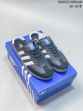 Dark gray Adidas Samba-style mule sneakers with white stripes, shown on a blue shoe box