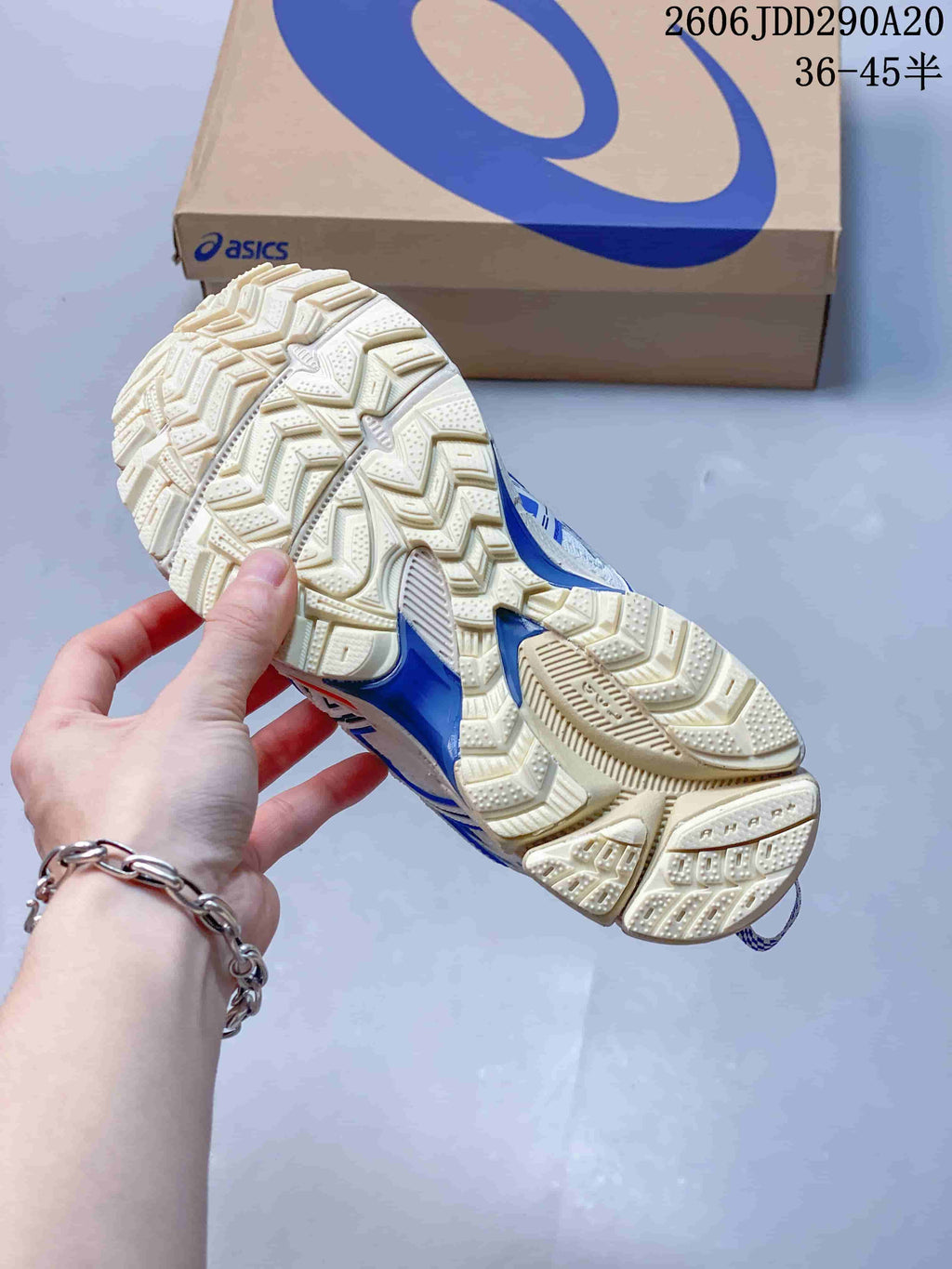 Close-up of the patterned outsole on a white and blue ASICS sneaker.