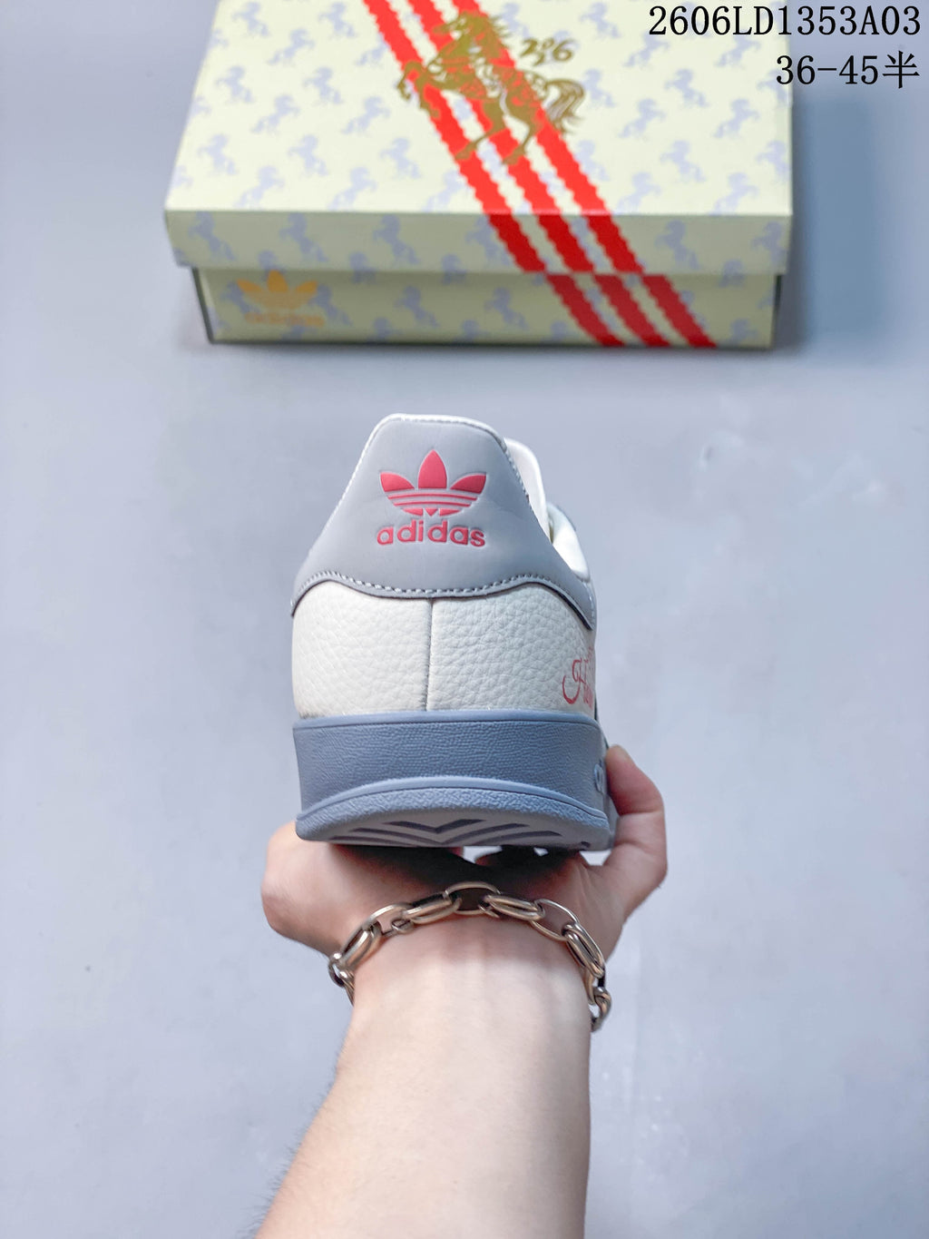 Rear view of a white and grey sneaker with red heel branding