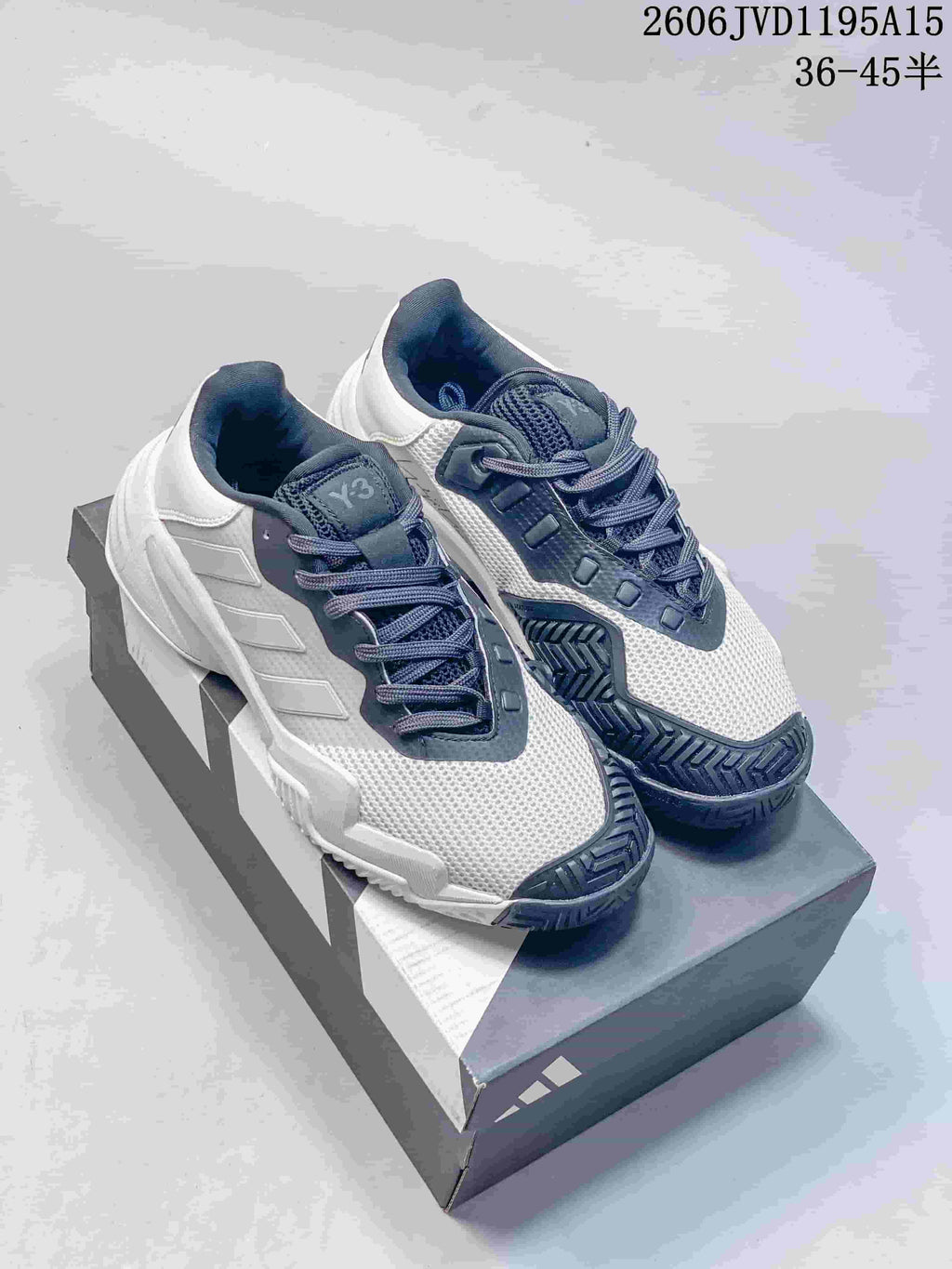 White and dark gray Y-3 Barricade 13 low-top sneakers, photographed as a pair on a shoe box.