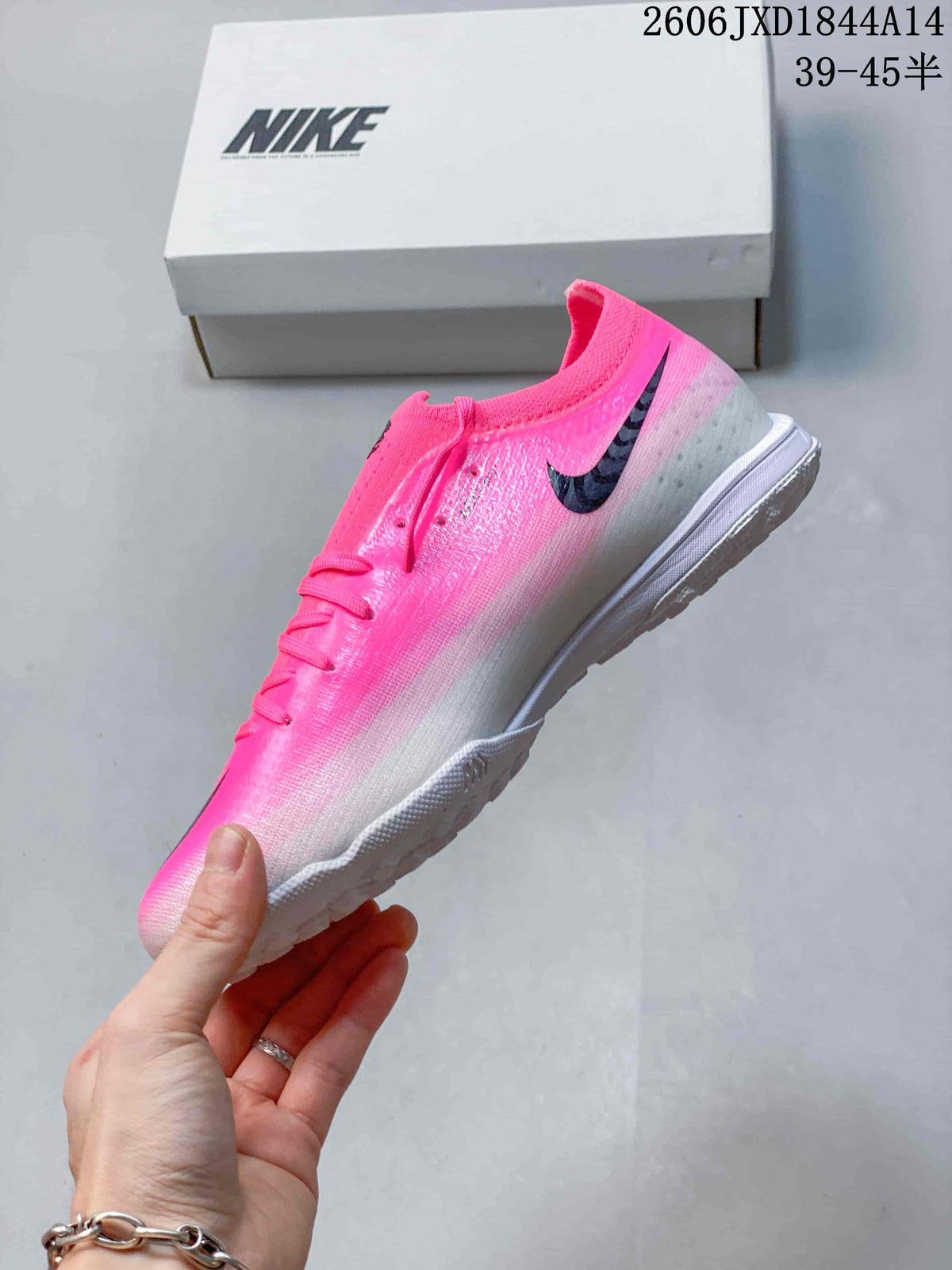 Side view showing the pink-to-gray gradient and black Swoosh on a Nike soccer cleat.