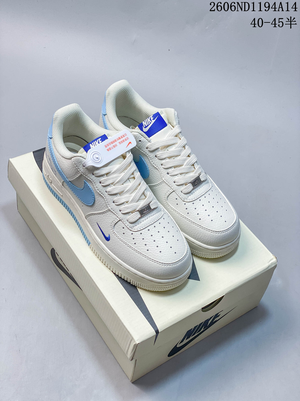 Pair of white Nike Air Force 1 '07 Low sneakers with light blue accents, photographed on a shoebox.