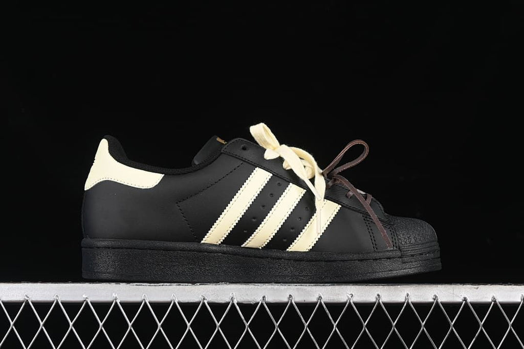 Side profile of the black adidas Superstar with cream stripes and heel detail.