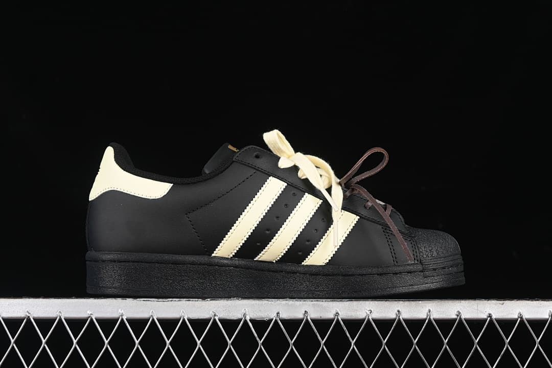 Side profile of the black adidas Superstar with cream stripes and heel detail.
