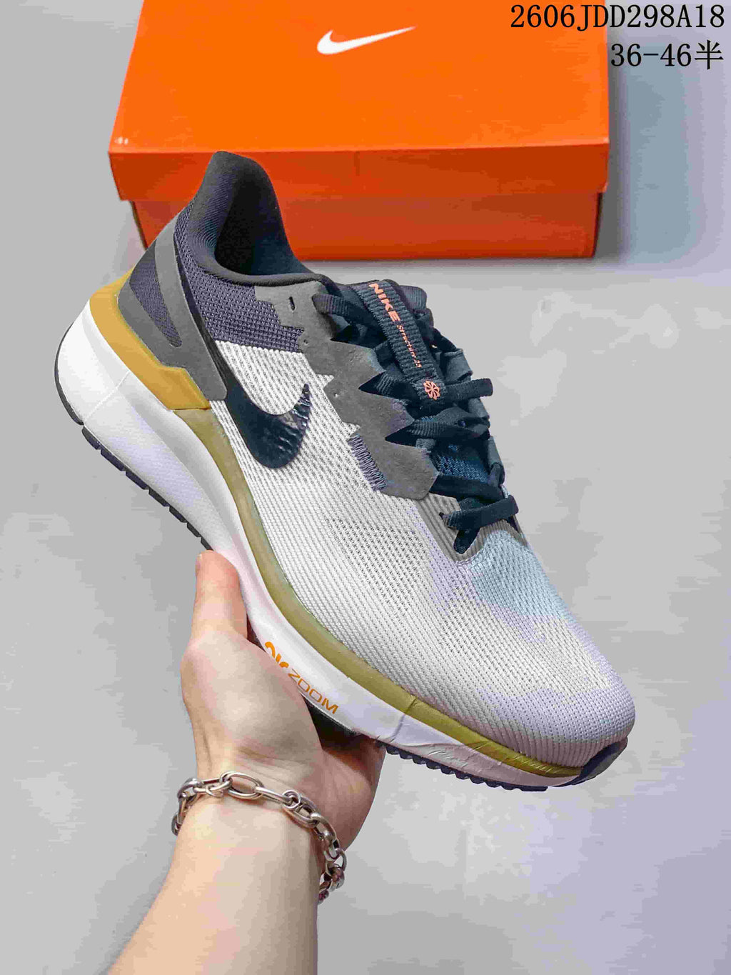 Side view of a white and grey Nike running shoe with dark laces and gold-toned accents