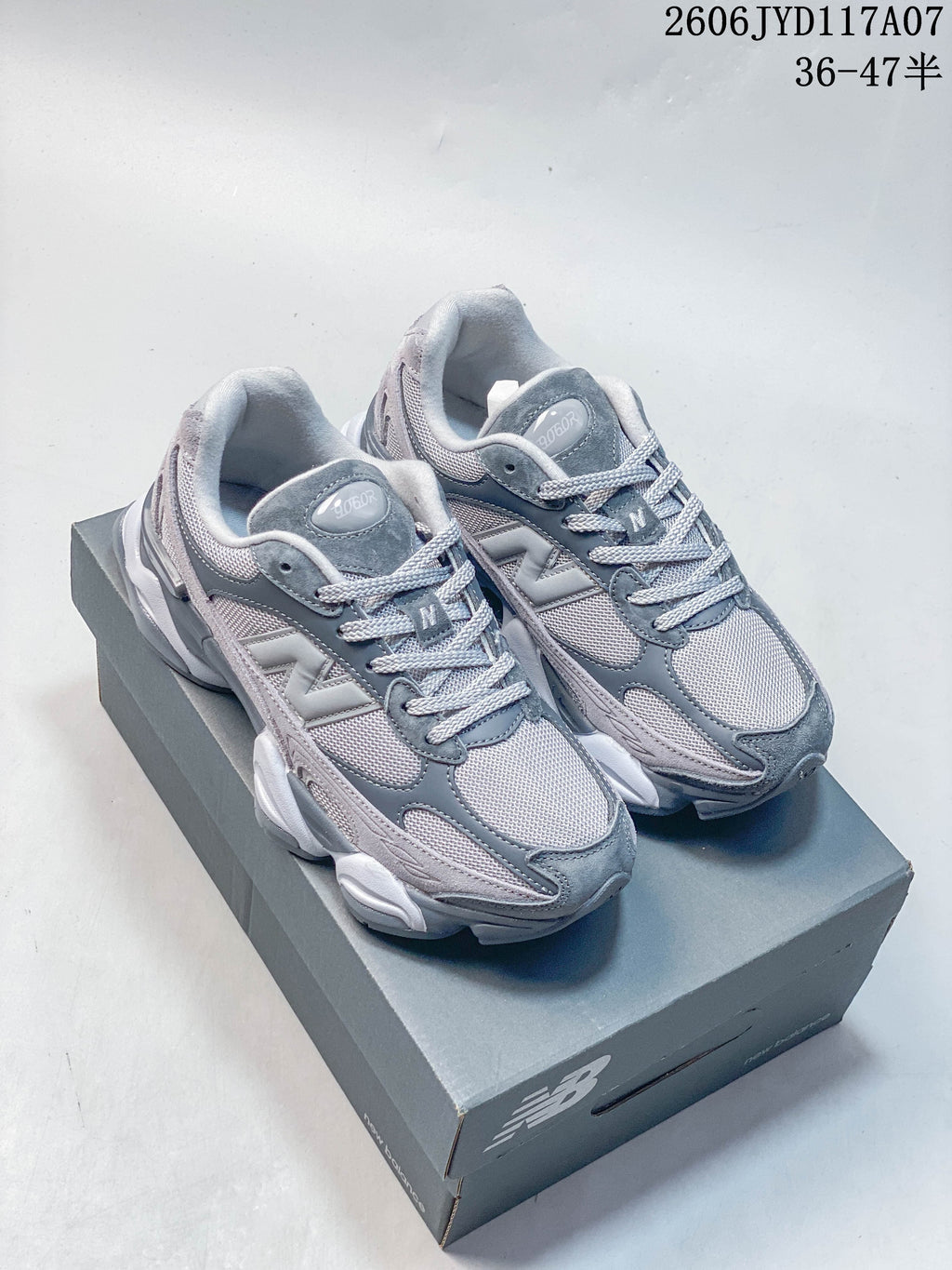 Pair of grey New Balance 9060 sneakers shown at an angle on a shoebox
