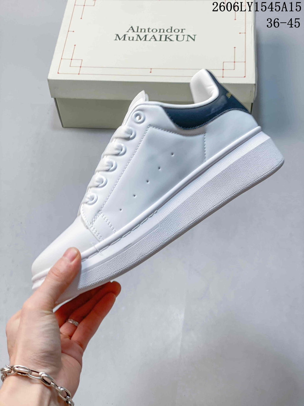 Side view of a white low-top sneaker with a navy heel tab and thick sole.
