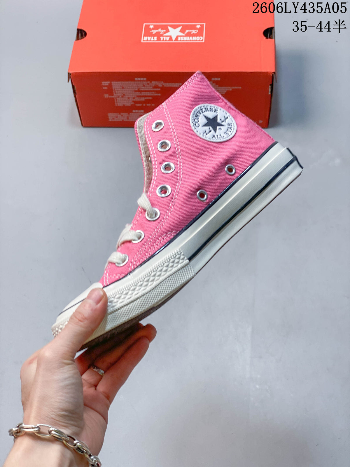 Side view of a pink high-top sneaker with white laces and a striped sole