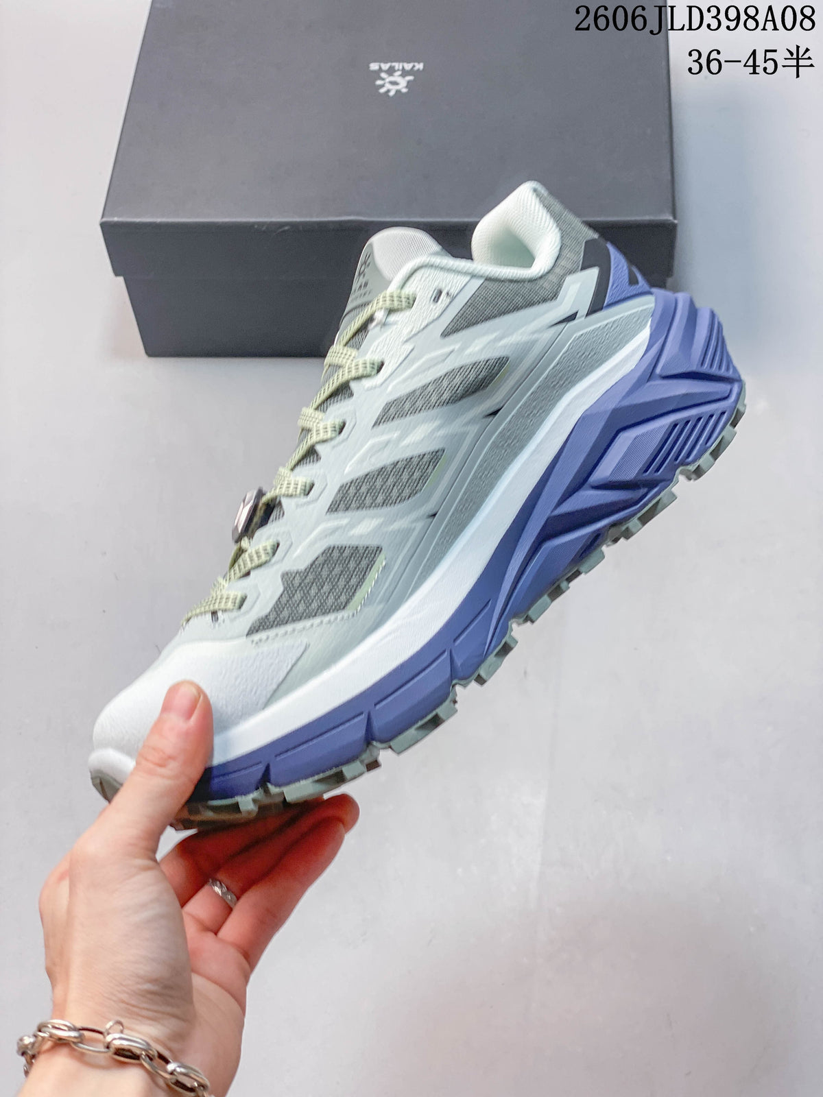 Side profile of the gray and white trail shoe with lavender midsole accents