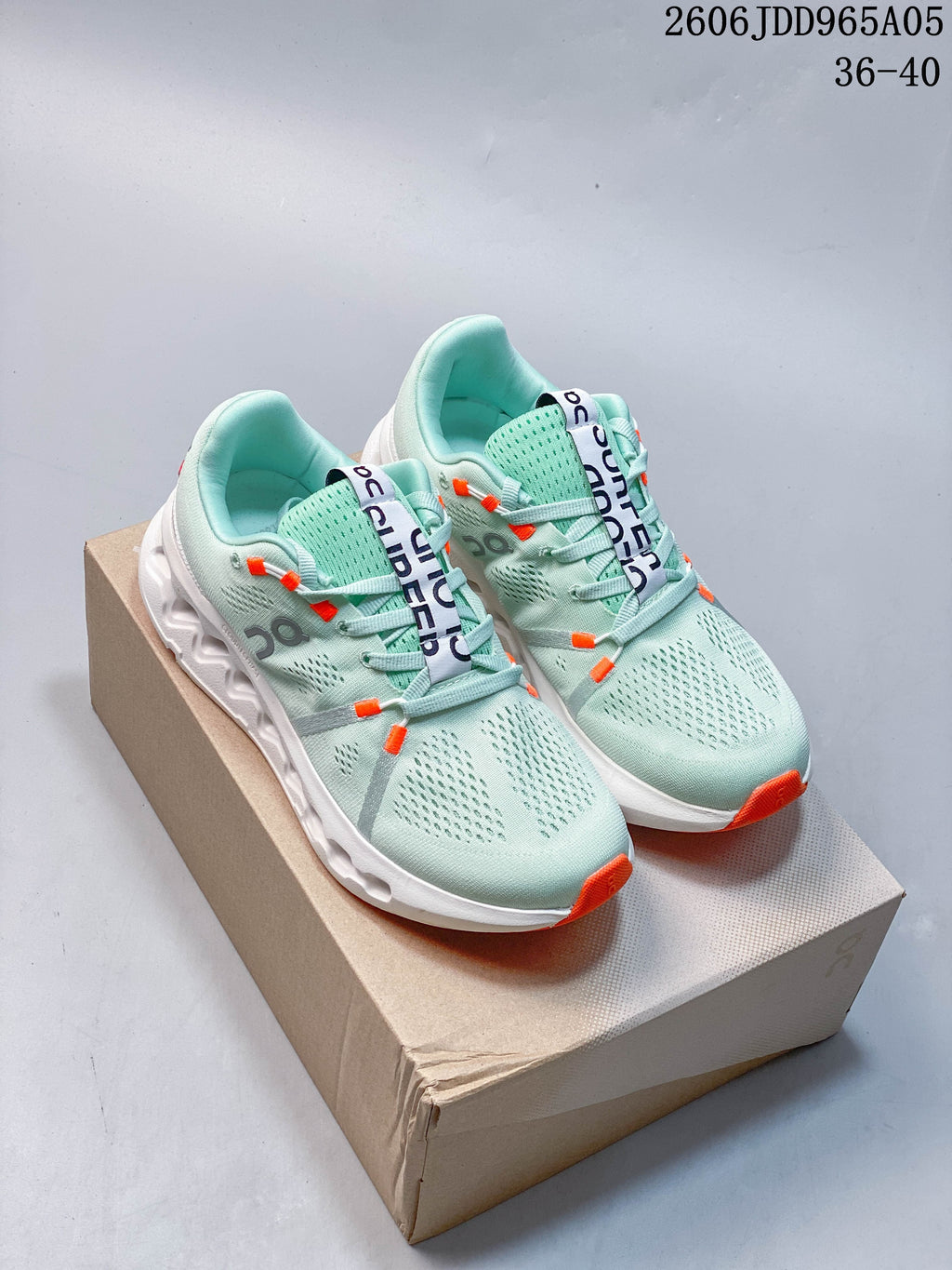 Pair of pale mint On Cloudsurfer Trail shoes with white soles and orange accents