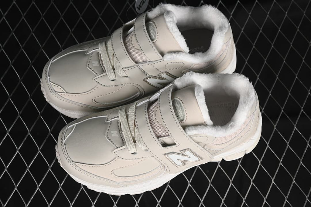 Pair of beige kids’ sneakers showing the straps, laces, and lined collars