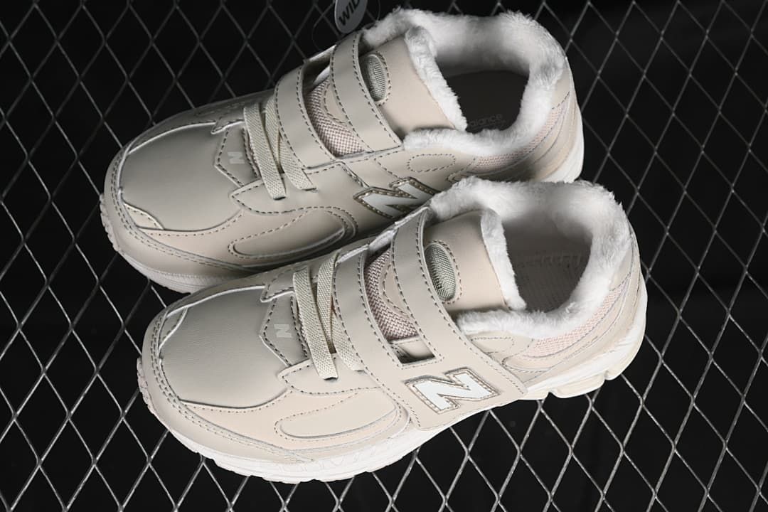 Pair of beige kids’ sneakers showing the straps, laces, and lined collars