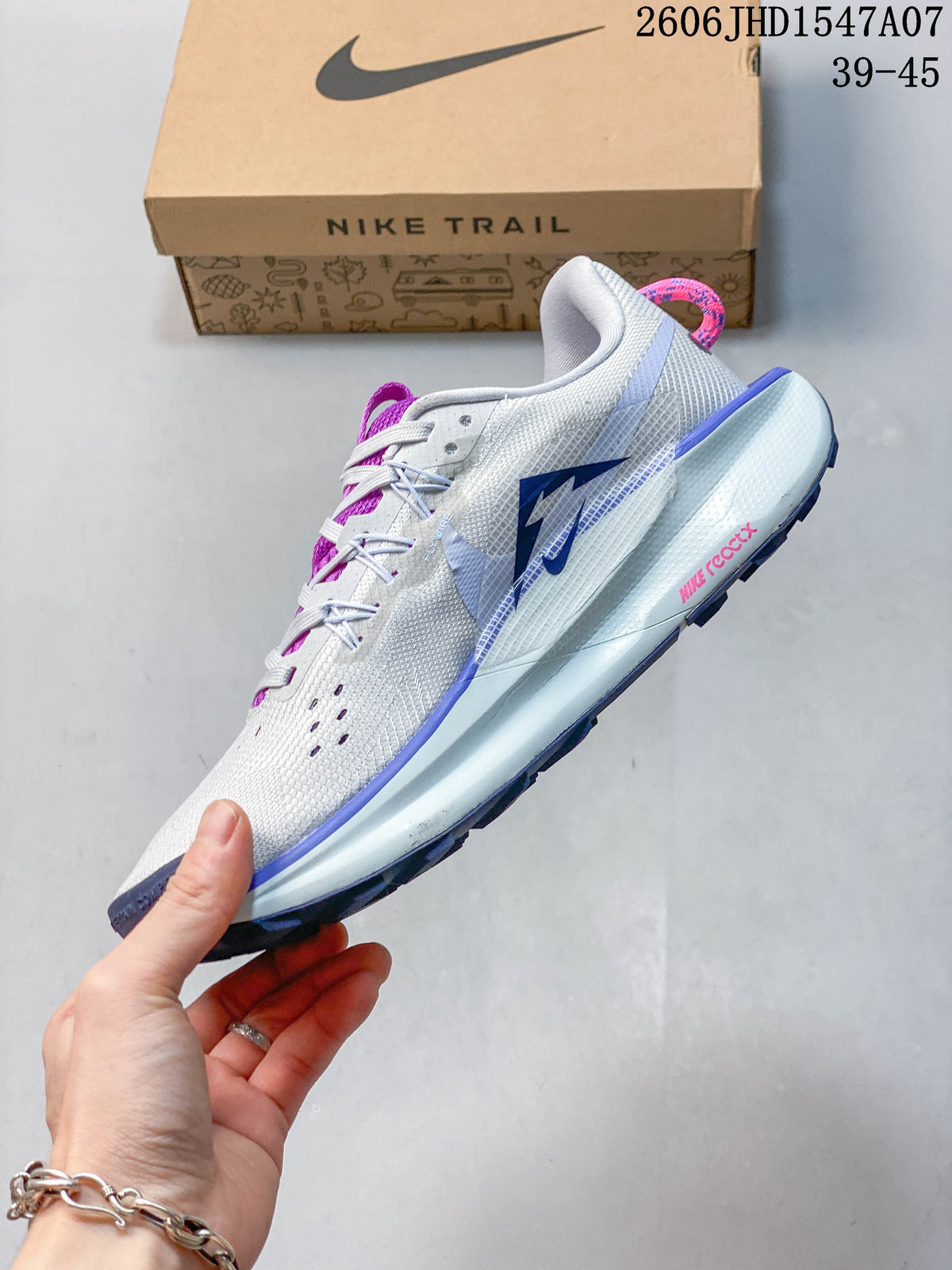 Side view of a gray Nike ReactX Pegasus Trail 5 trail running shoe with blue and purple accents.