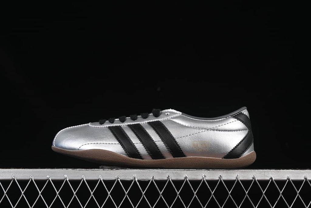 Side profile of silver adidas Tokyo Decon W sneakers with black stripes and gum-colored outsole