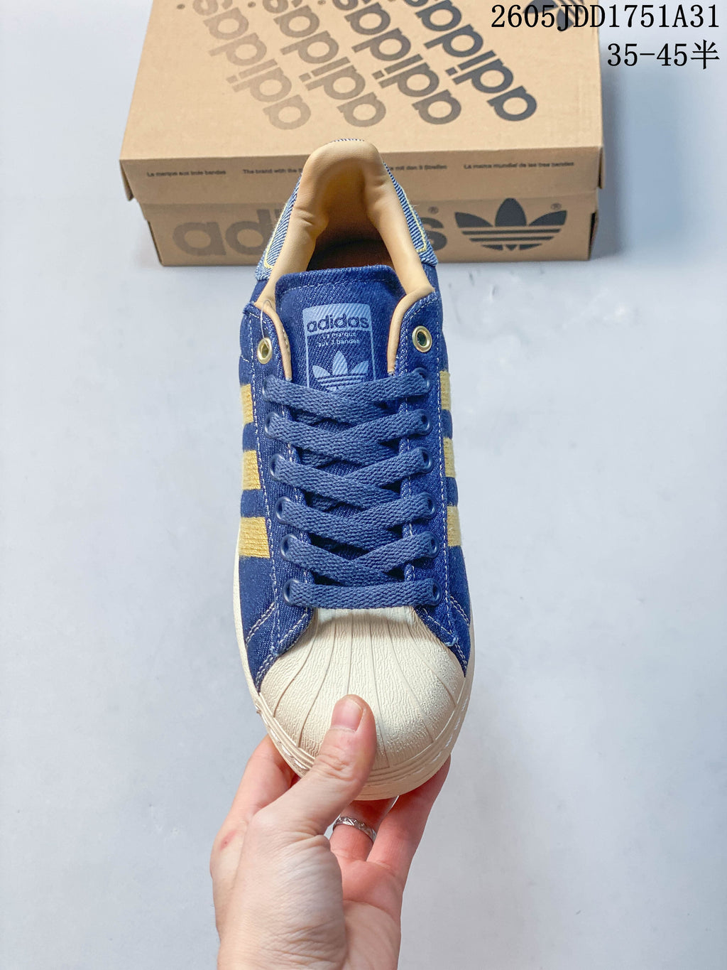 Front view of a blue Adidas Superstar sneaker with blue laces and a cream shell toe