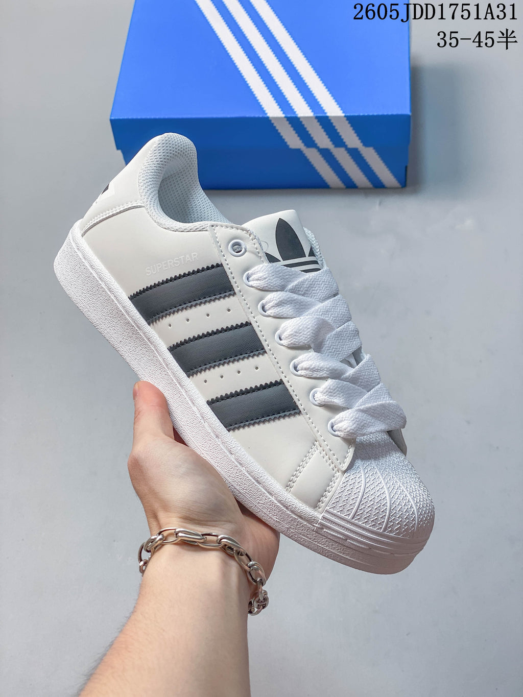 White Adidas Superstar-style sneaker with gray stripes and a molded shell toe