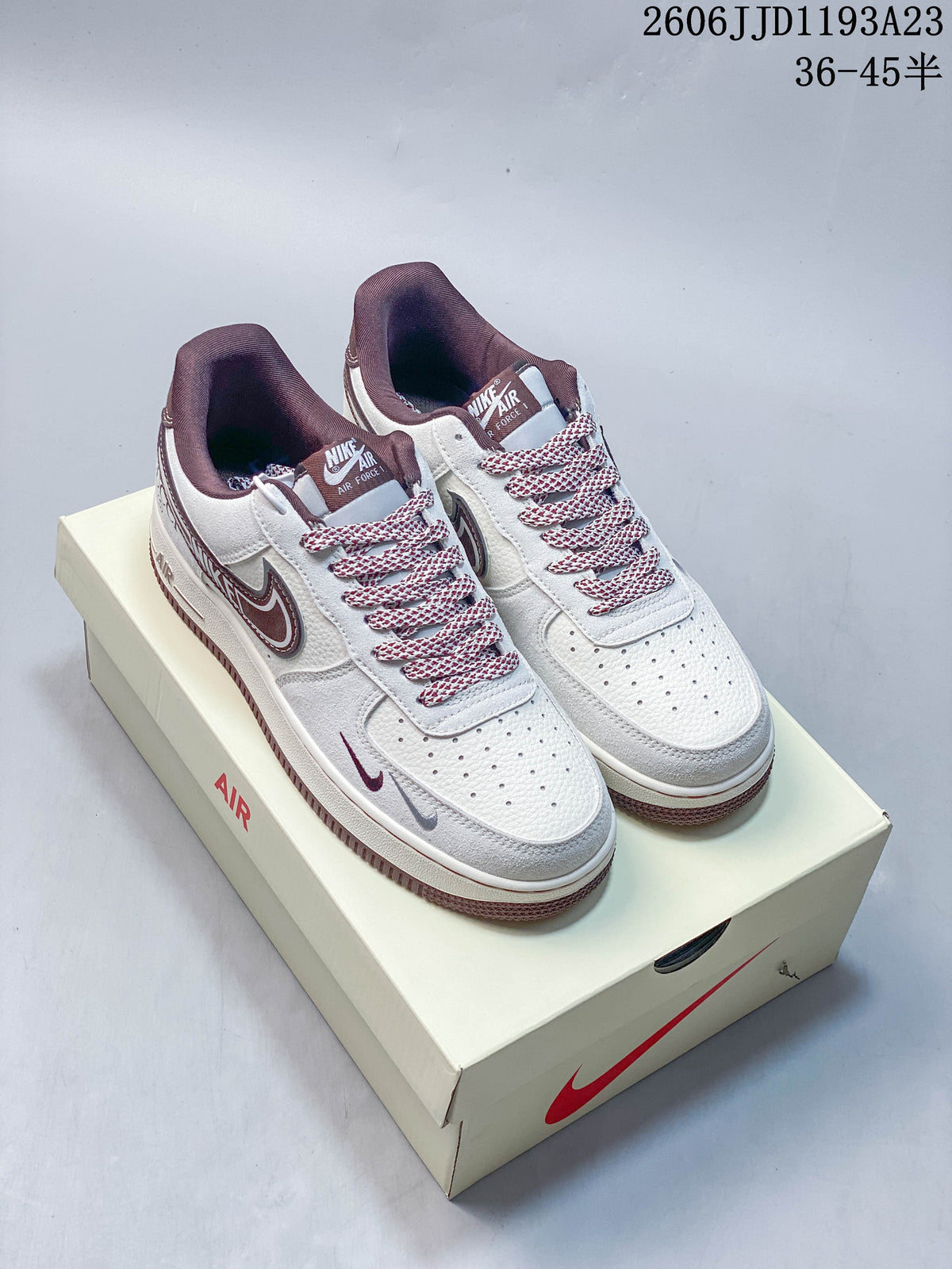 White and burgundy Nike Air Force 1 sneakers shown from above on a shoe box