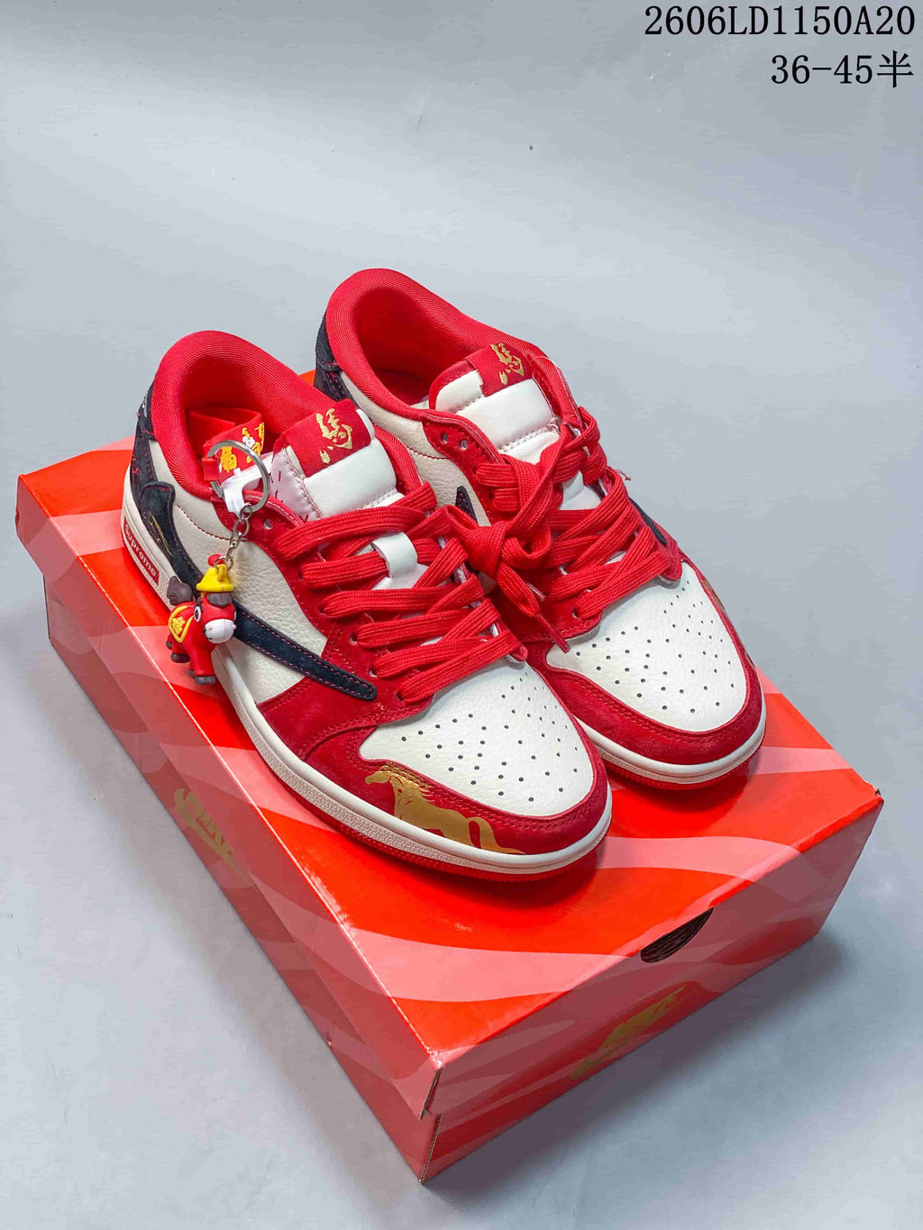 Pair of red, white, and navy low-top sneakers with decorative charms on a patterned box