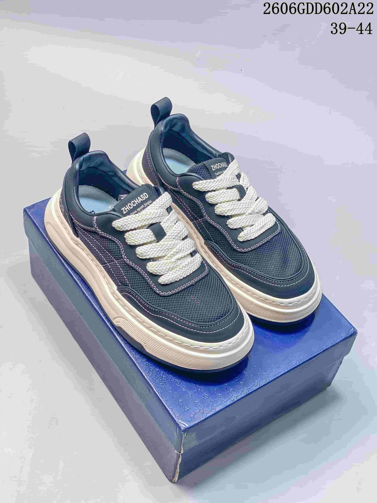 Pair of navy low-top lace-up sneakers with white laces and contrasting thick soles.