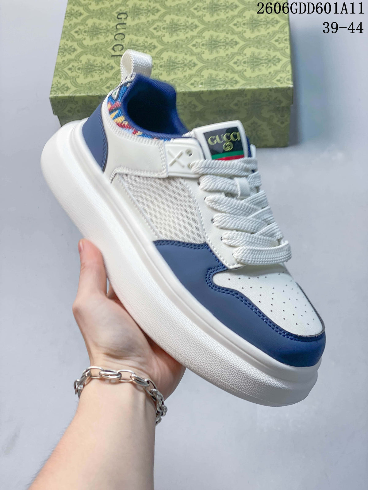 Angled view of the white and blue sneakers with mesh side panels and embroidered collar trim.