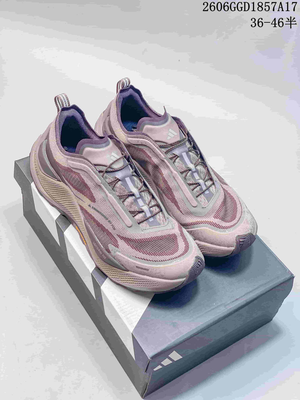 Pair of muted pink adidas HOLO PEAK trail shoes on a shoebox.