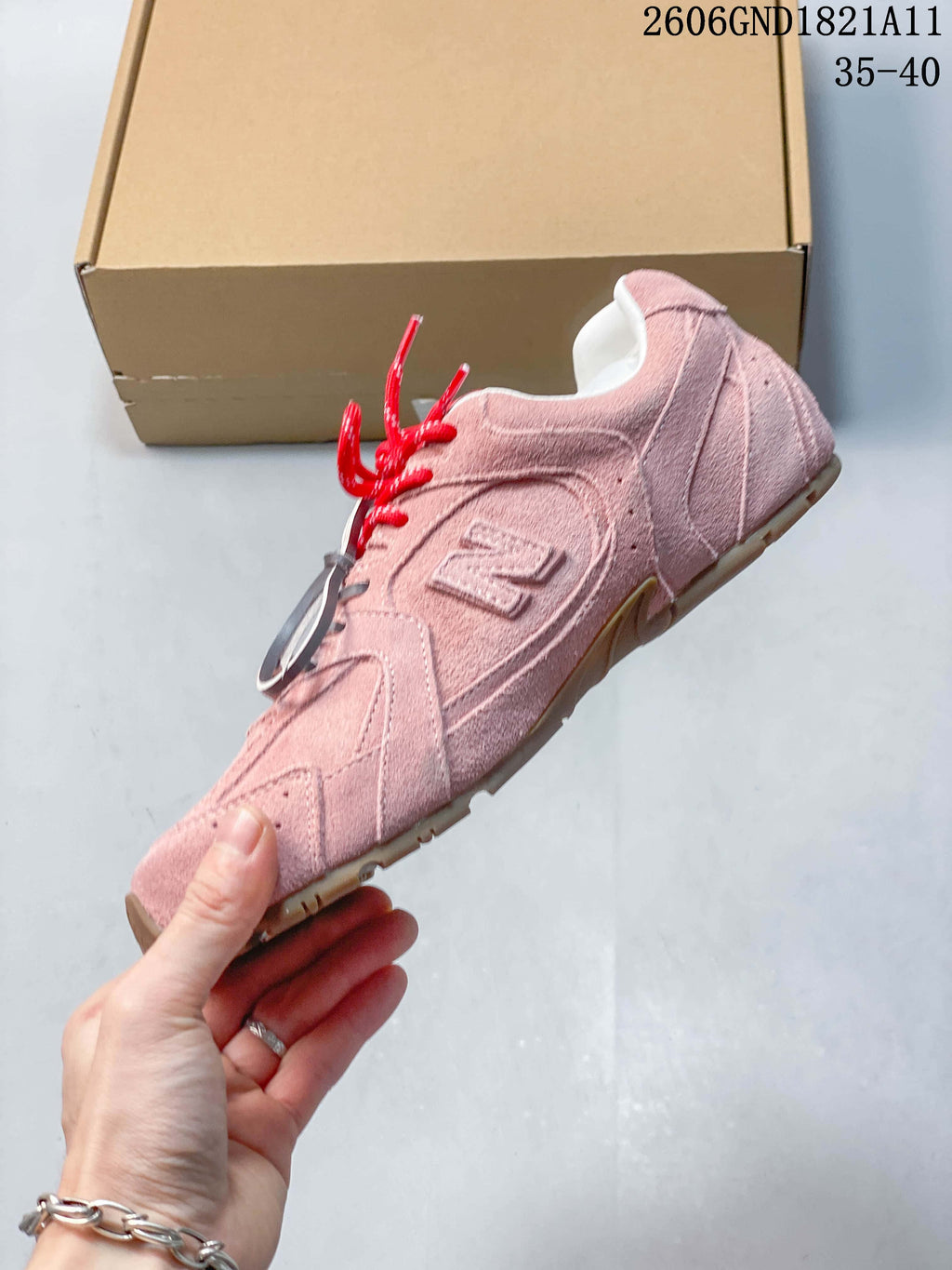 Side view of a pink sneaker with layered panels and a raised side logo