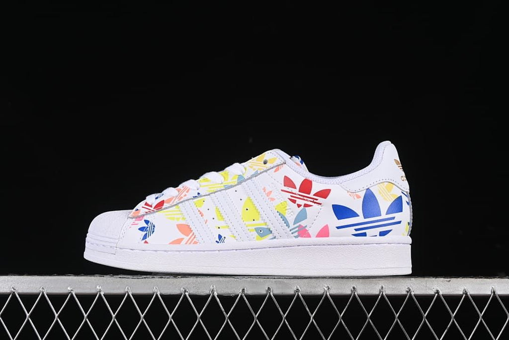 Side profile of white adidas Superstar sneakers with colorful graphic print and shell toe