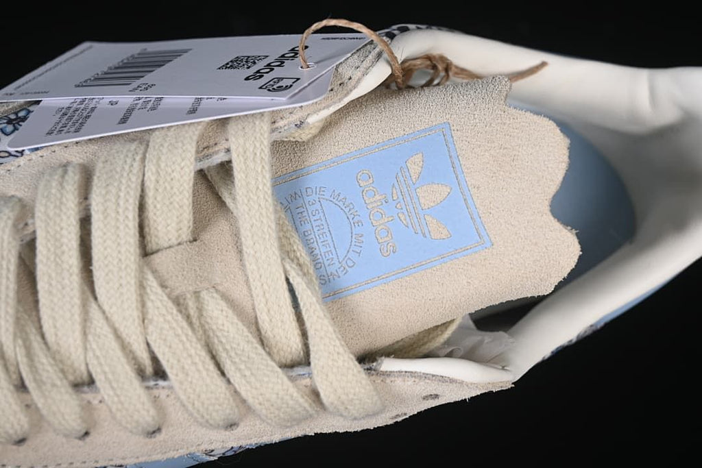 Close-up of cream laces and tongue label on the floral-print sneaker