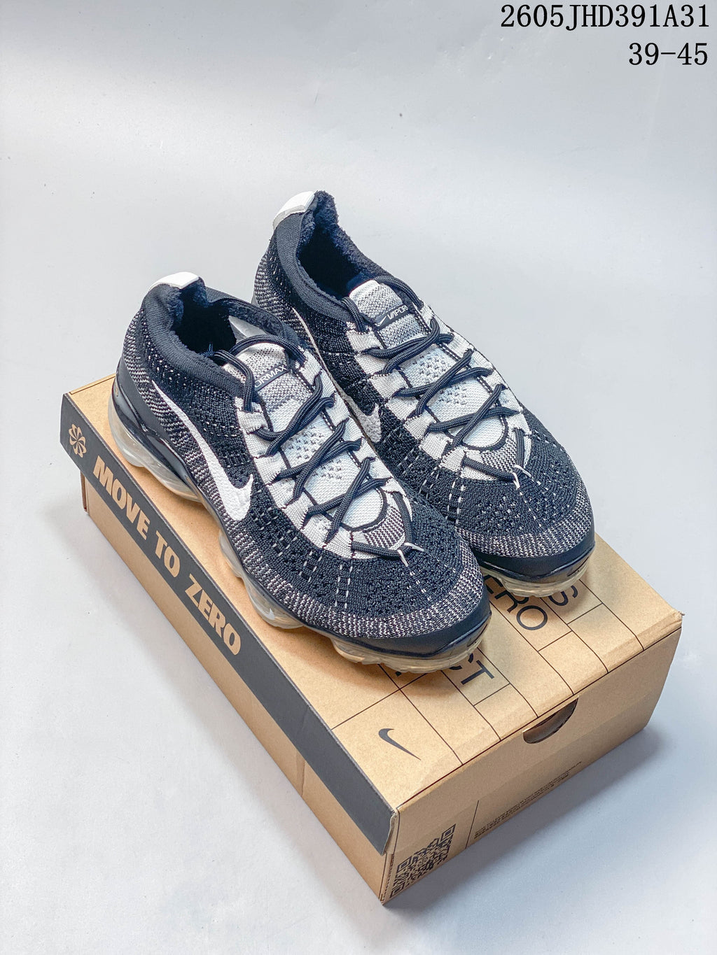 Pair of navy, gray, and white Nike Air VaporMax 2023 Flyknit-style running shoes on a Move to Zero box