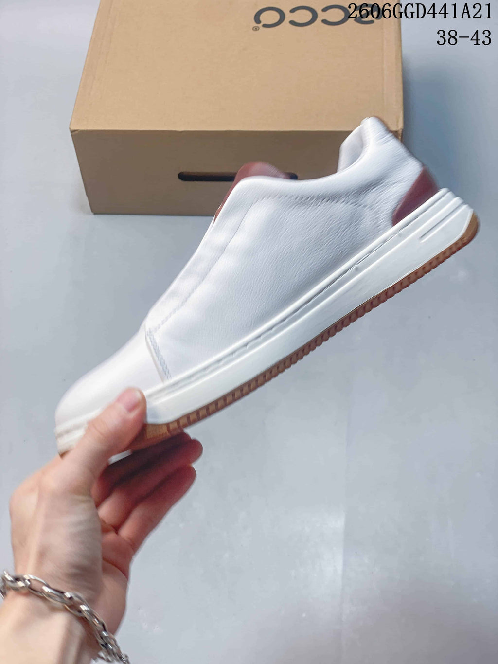 Side profile of the white sneaker with brown heel detailing and gum-colored outsole.