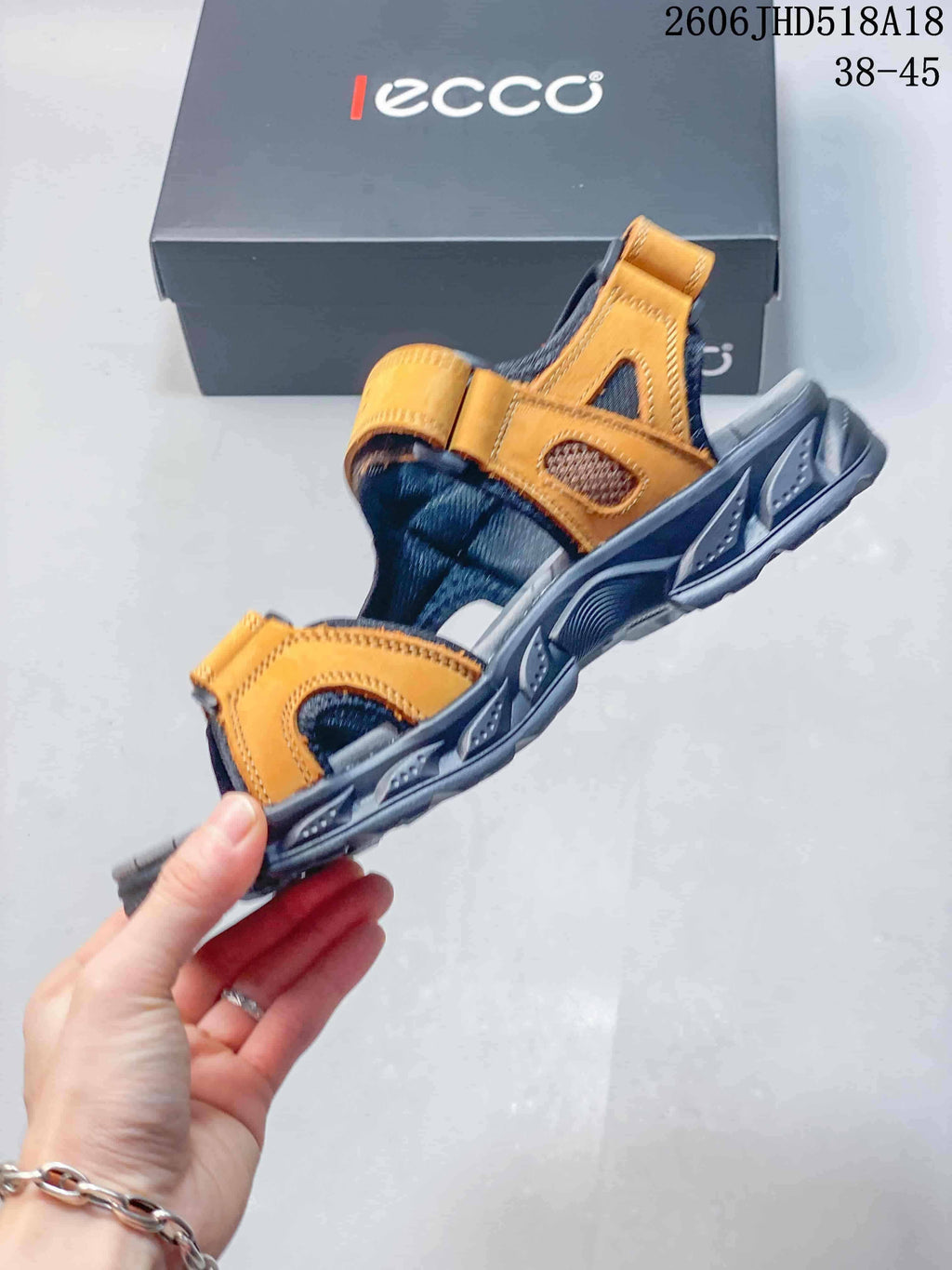Side view of an orange and gray open-toe sandal with adjustable straps and mesh-like panels.