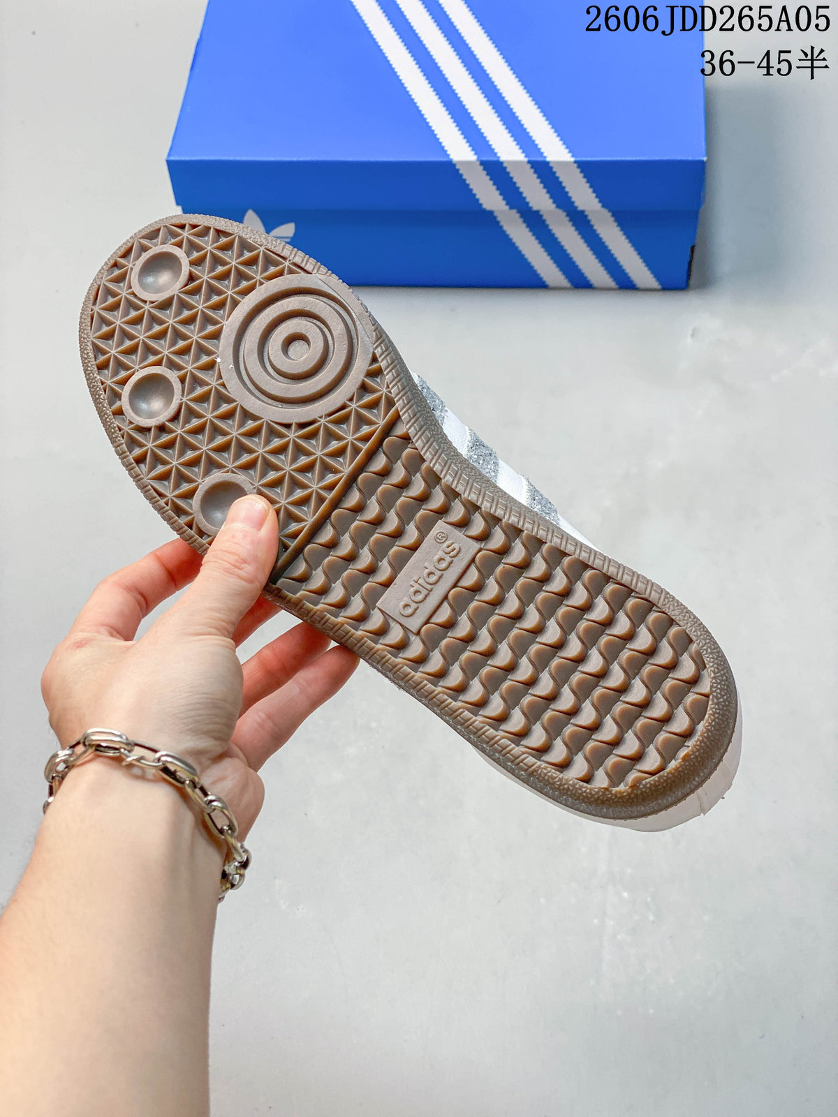 Close-up of the gum-colored patterned outsole on a white Samba OG sneaker.