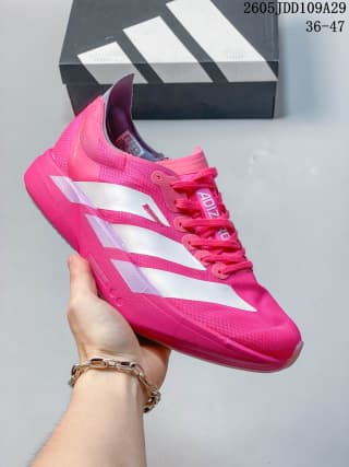 Pink Adidas running sneaker held in front of an Adidas shoebox.