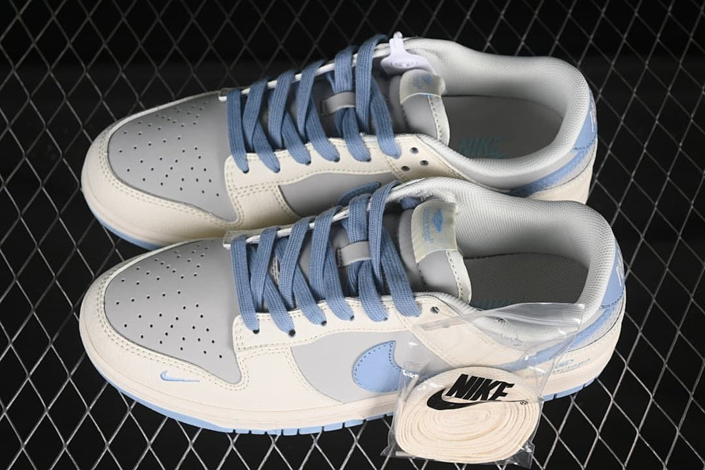 Overhead view of a pair of cream and grey low-top sneakers with blue laces and a spare lace set.