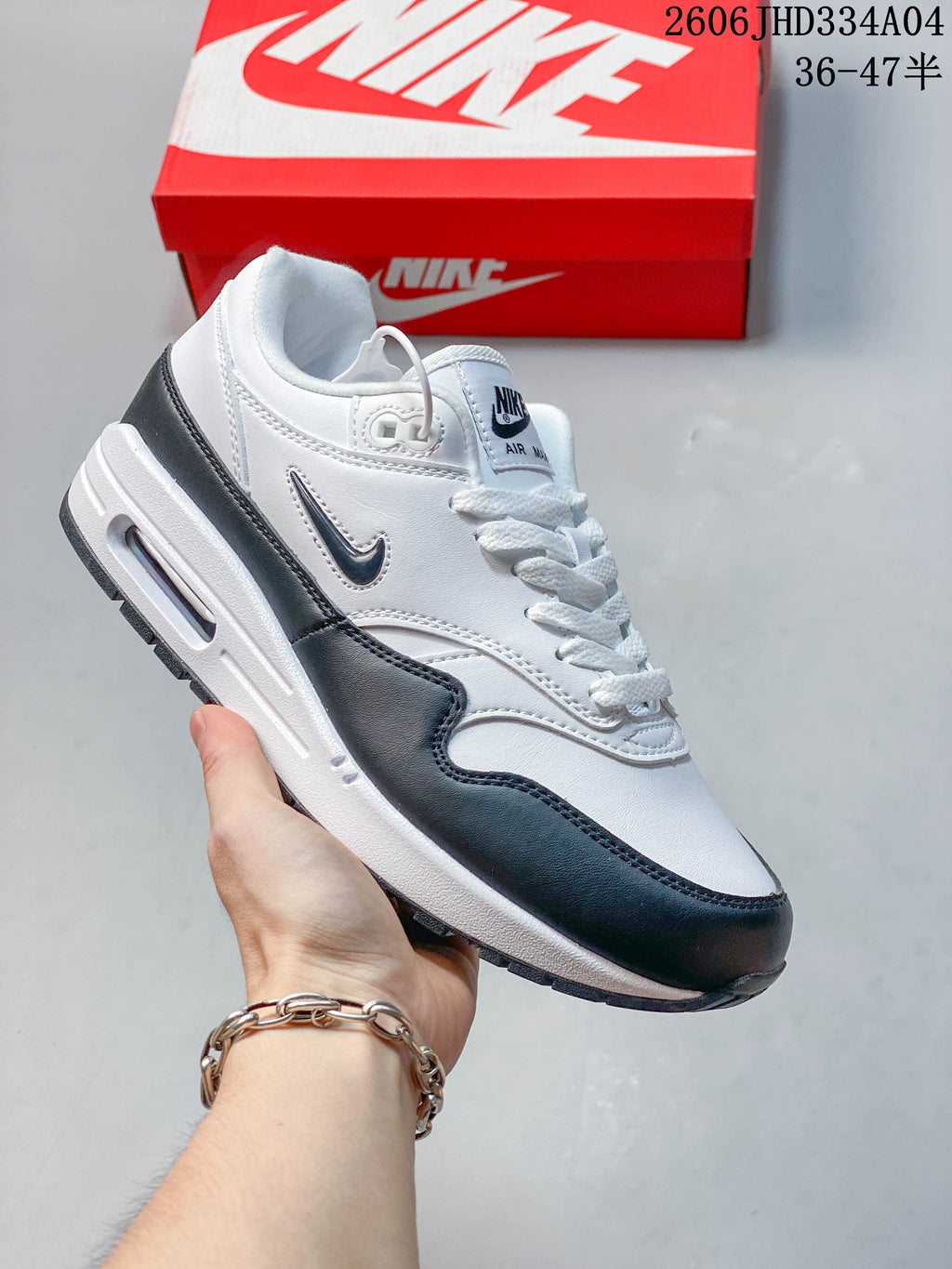 White Nike Air Max 1 sneaker with beige overlays and a metallic gold-tone Swoosh.