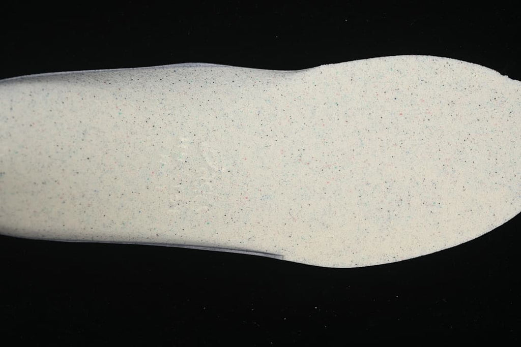 Close-up of a light-colored sneaker sole with small speckles.