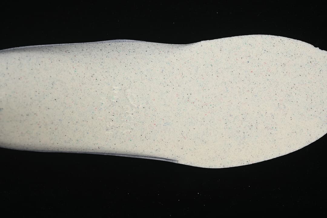 Close-up of a light-colored sneaker sole with small speckles.
