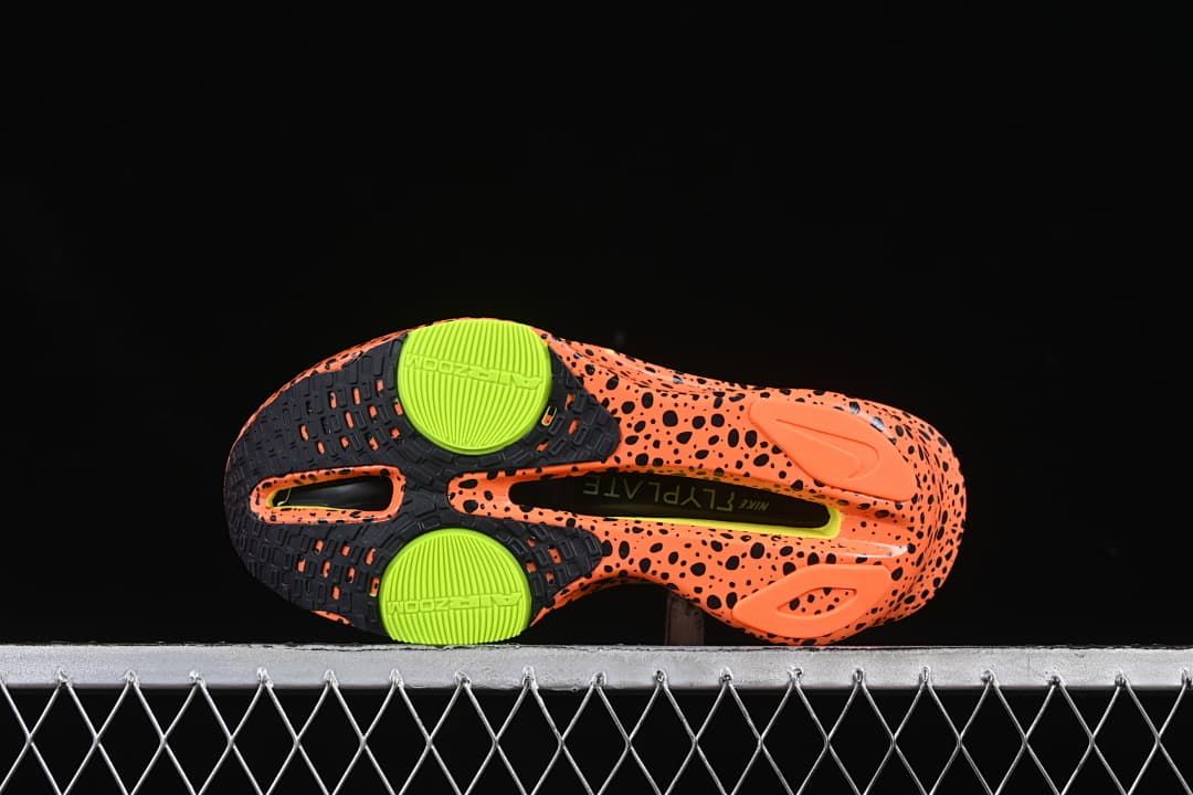 Outsole view with orange speckles, dark traction areas, and lime circular details.