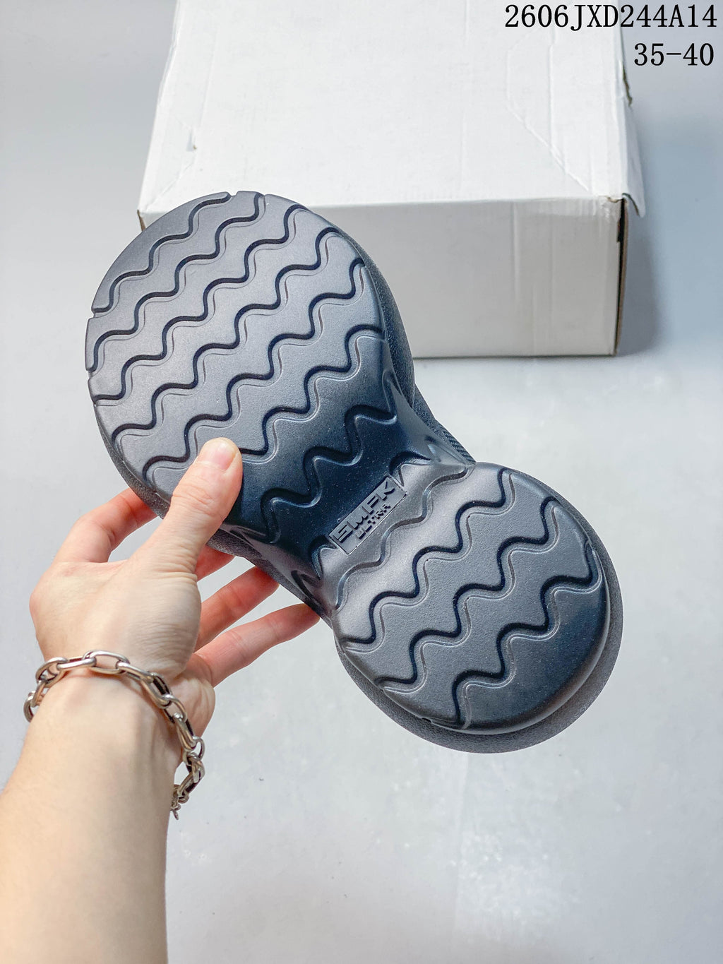 Underside of a charcoal sneaker showing a wavy-patterned outsole.