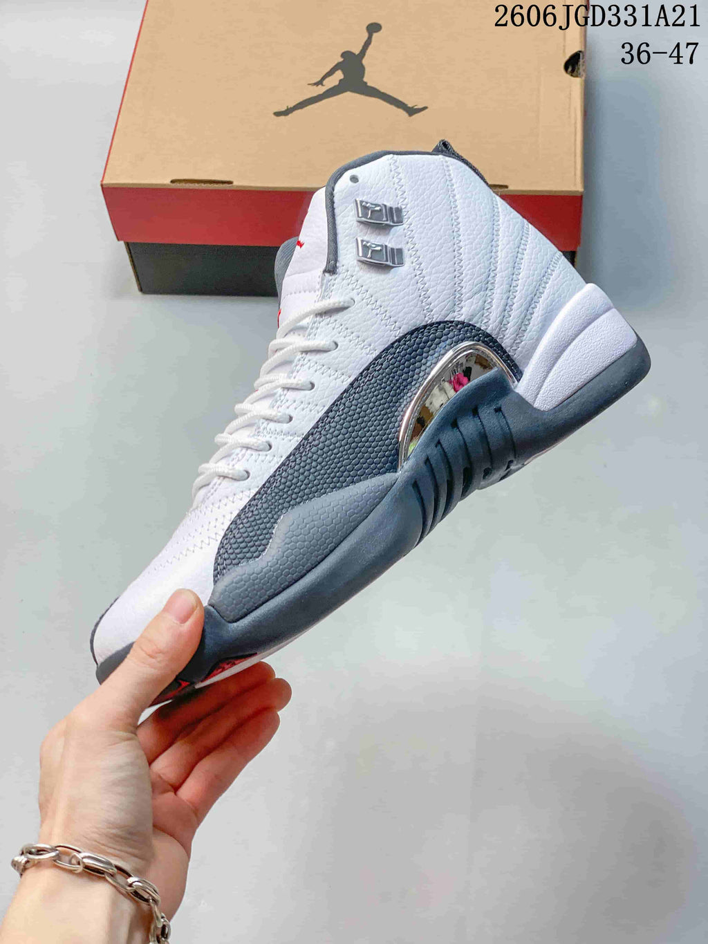 Side view of a white and grey Air Jordan 12 high-top shoe with textured panels