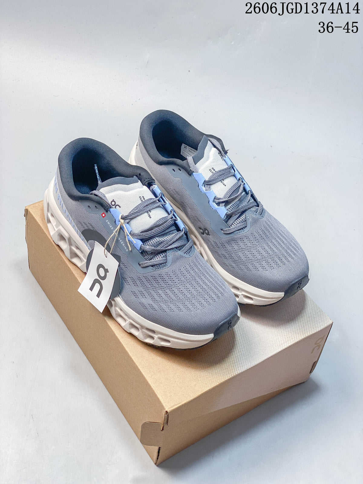 Pair of grey On Cloudmonster 3 shoes with light blue accents on a box.