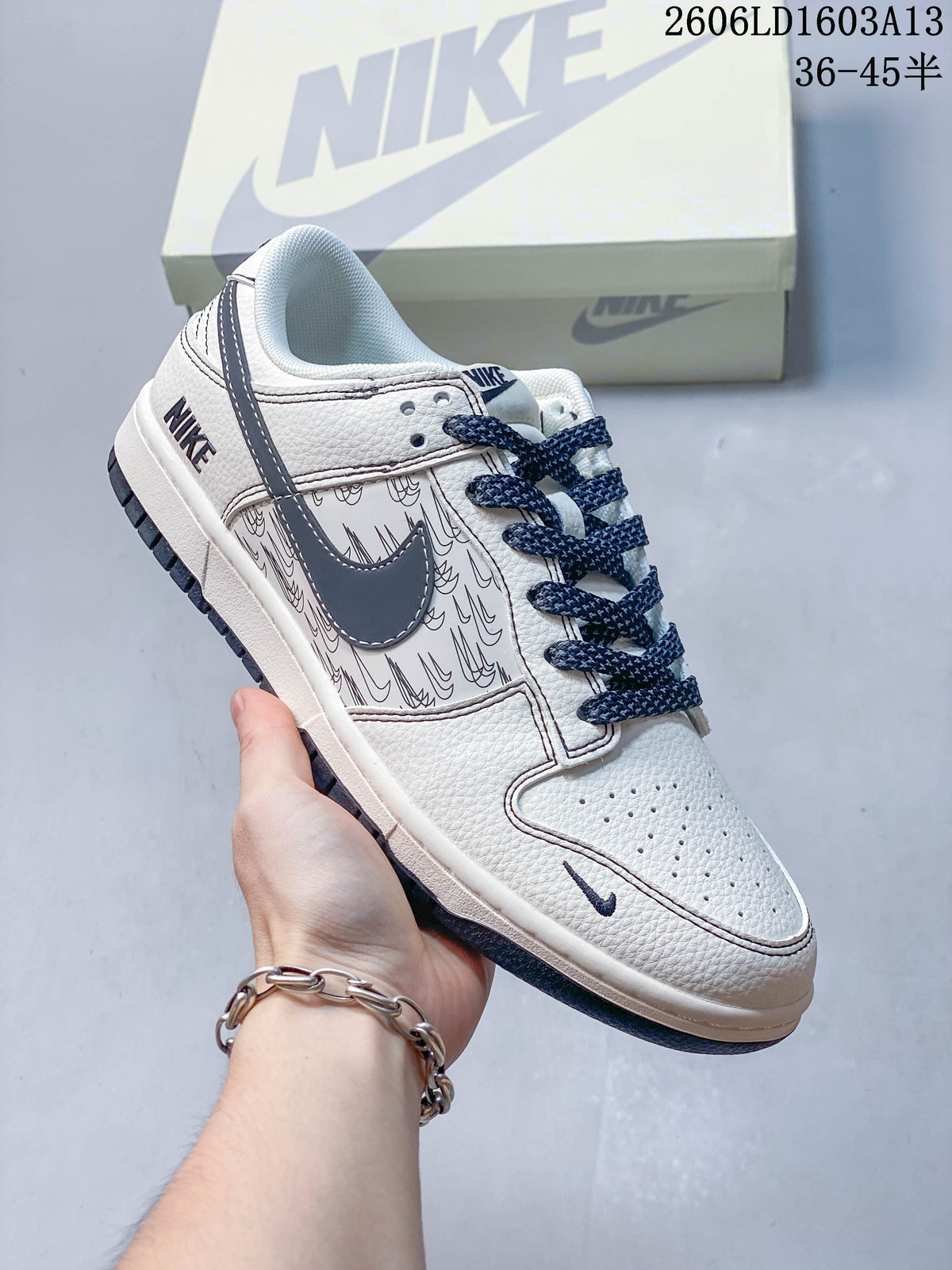 Angled view of the cream low-top sneaker with navy accents and patterned side panels.