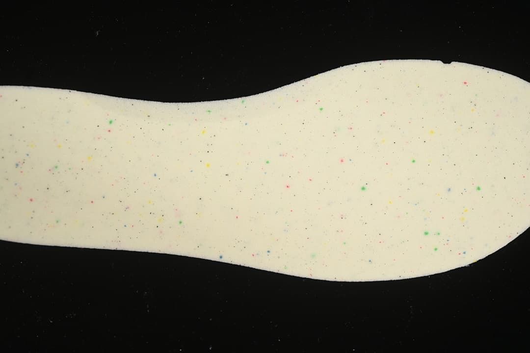 Close-up of a light-colored shoe insert with multicolored speckles.