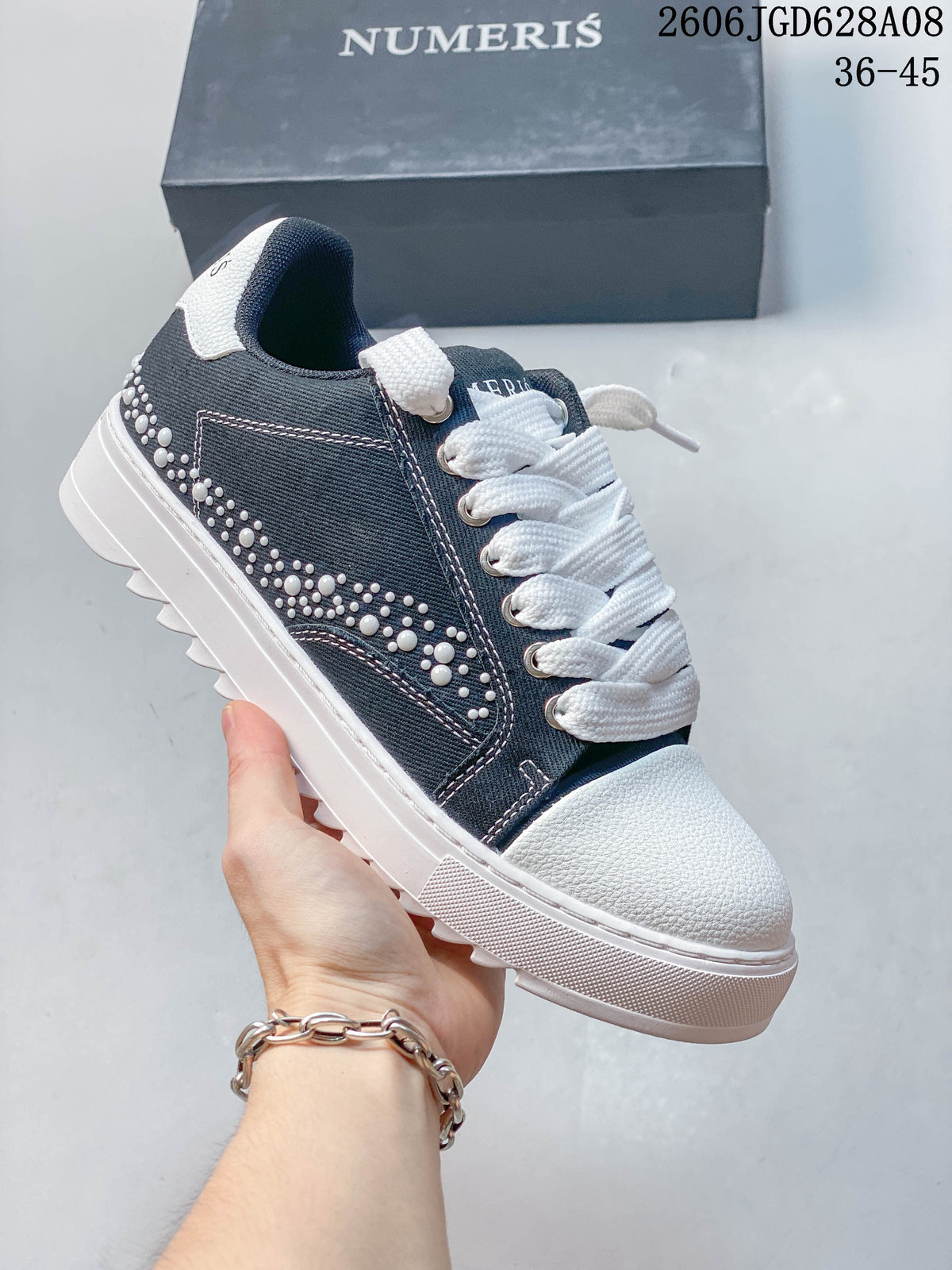 Dark gray sneaker with white stud embellishments along the side.