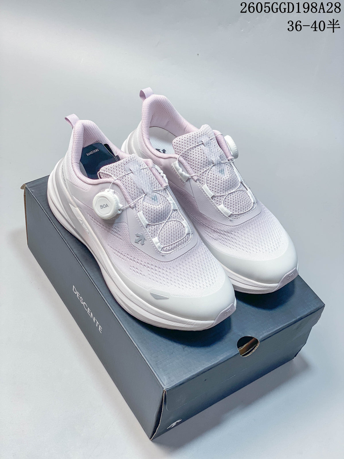 White and pale lavender DESCENTE running shoes with BOA dial closure, shown on their box.